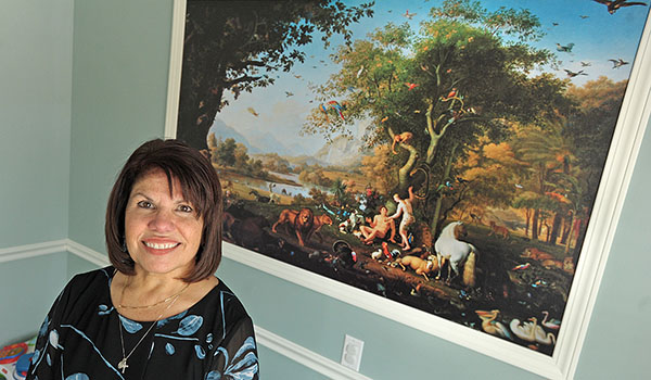 Gloria M. Roetzer, MD, owner of Trinity Pediatrics, stands in her waiting room in front of a print of Adam and Eve. Roetzer opened her practice to combine Catholic teaching and medical care. (Dan Cappellazzo/Staff Photographer)