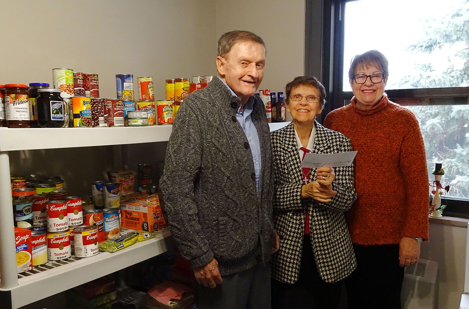 Sister Marie Andre Main, center, poses with HOPE Committee members Frank and Christine O'Connor in Trocaire's student food pantry, Catherine's Cupboard. (Courtesy of Trocaire College)