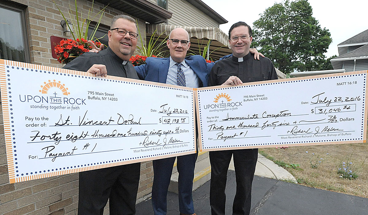 On behalf of their parishes, Frs. Robert Hughson and James Bastian accept Upon This Rock disbursements from Richard C. Suchan, Executive Director of the Foundation of the Roman Catholic Diocese of Buffalo. The money received will help the parishes of St. Vincent de Paul (including the Prince of Peace & St. Leo worship sites) in Niagara Falls and Immaculate Conception in Ransomville. (Patrick McPartland/Staff Photographer)


