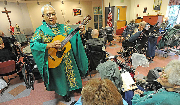 Father Ivan Trujillo sings and plays guitar during Mass to area veterans in Batavia at the New York State Veterans Home Chapel. (Photo by Dan Cappellazzo/Staff Photographer)