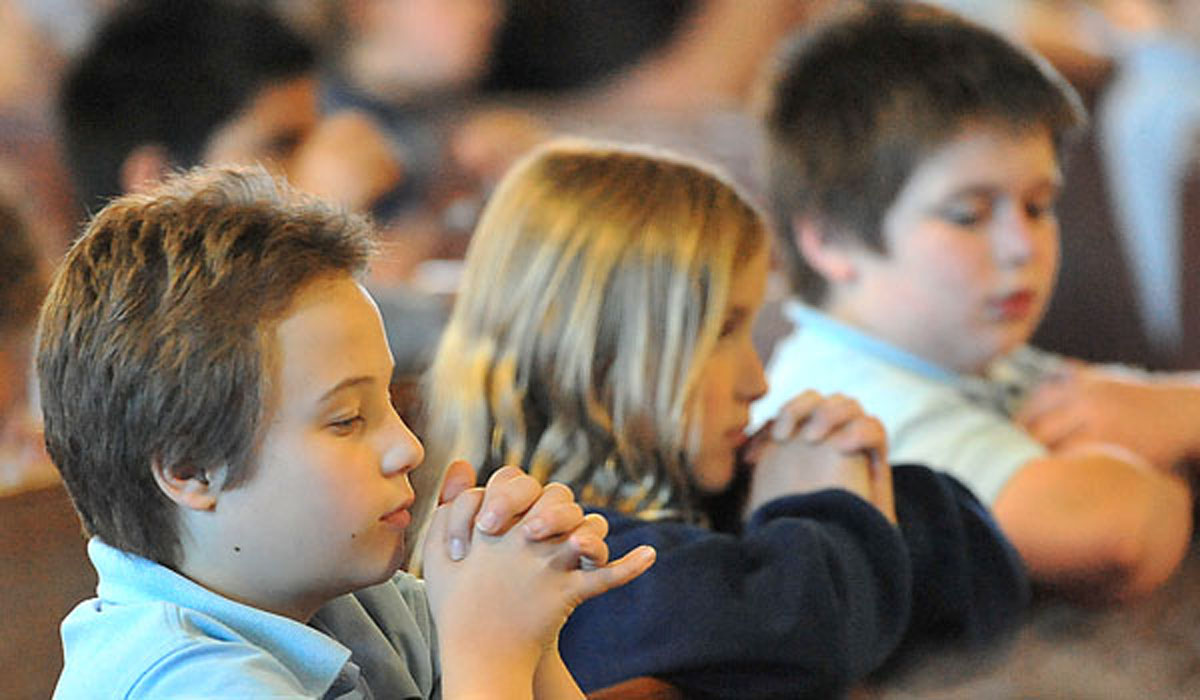 William Strusienski, Sydney Slazak and Benjamin Solomon students at Mary Queen of Angels School pray for the seminarians in the diocese. 
(WNYCatholic File)