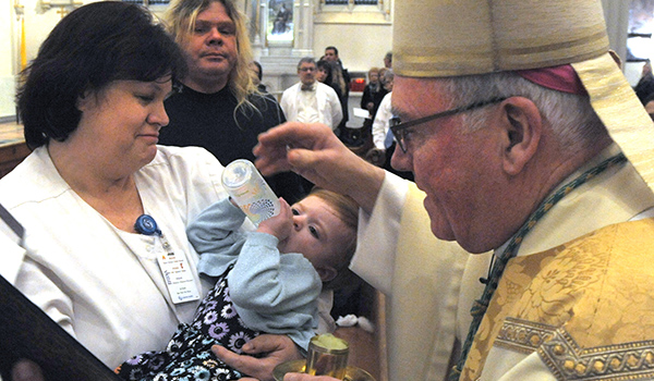 At the annual White Mass, on February 10, 2017, Bishop Richard J. Malone anointed one year old Olivia Margaret Regis, who had open heart surgery at only seven days old. She is held by her grandmother Julie Kuster. Family friend Robert Raczka looks on. 
 The annual White Mass at St. Joseph Cathedral acknowledges the important role of healthcare workers and includes Anointing of the Sick. Dan Cappellazzo/Staff Photographer