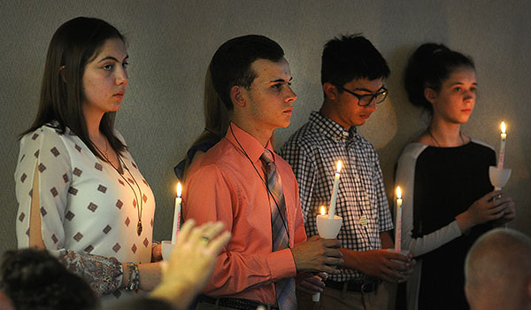 Four of the 12 new members of the 2018-19 Diocesan Youth Board hold candles during a ceremony at the Catholic Center. Outgoing members light the candles of new members as they pass the torch to a new group of Catholic teen leaders. (Dan Cappellazzo/Staff Photographer)