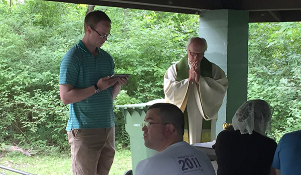 Michael Halloran from St. Leo the Great Parish in Amherst recites the first reading from an iPad during an outdoor Mass at Ellicott Creek Park. The July 22 Mass was hosted by St. Benedict Parish in Eggertsville for young adults. Father Robert Mock, pastor of St. Benedict's, celebrated the Mass. (Patrick J. Buechi/Staff)