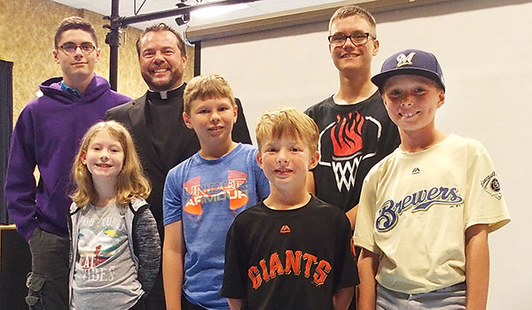 Father David Richards poses with a group of young people from Our Lady of Pompeii Parish who attended Move Under the Stars. The event had to be moved indoors due to weather, but this did not put a damper on their great time.