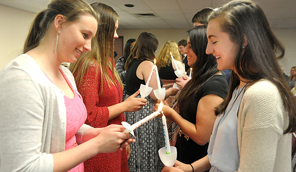 Outgoing Diocesan Youth Board member, Clare Ahne (left) passes her candle light to new incoming Youth Board member Sarah Wellence (right) as the 2016-2017 Diocesan Youth Board is installed during ceremonies at the Catholic Center. (Patrick McPartland/Managing Editor)