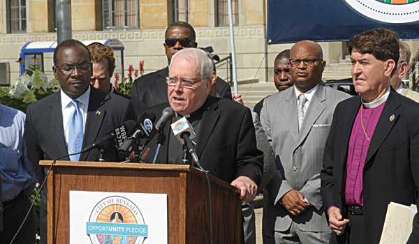 Bishop Richard J. Malone (center) speaks about economic justice during Wednesday's press conference, which included Buffalo Mayor Byron Brown (far left) and Episcopal Bishop R. William Franklin (far right). (Patrick J. Buechi)