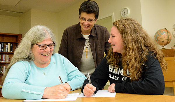 Margaret McDonnell-Alexander (seated left to right) and Sadie Cornelius, of the Care for Creation Committee at SS. Peter and Paul Parish in Hamburg, write letters to elected officials for greener policies.  Sister Jean Sliwinski, CSSF, from the diocesan Care For Creation Committee, looks on. (Patrick McPartland/Staff Photographer)