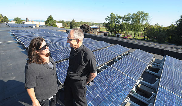 Diocesan Energy Director, Carol Ann Cornelius and Father Ross M. Syracuse, OFM Conv., pastor of St. Francis of Assisi Parish, check on the solar panels on the roof of the parish center. (Patrick McPartland/Staff Photographer)