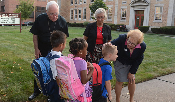 Carol Kostyniak (right), along with Bishop Richard J. Malone and Sister Carol Cimino, SSJ, greet students at Catholic Academy of West Buffalo on their first day of school. (Patrick McPartland/Staff Photographer)