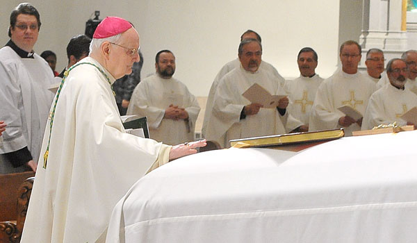 Bishop Emeritus of Erie, Bishop Donald Trautman, places his hand on the casket of Auxiliary Bishop Emeritus Bernard McLaughlin as Bishop Trautman enters St. Joseph Cathedral for a Mass of Christian burial for Bishop McLaughlin. (Patrick McPartland/Staff Photographer)