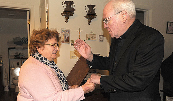 Bishop Richard J. Malone blesses Rosalia after delivering her Meals on Wheels food. He also gave her a rosary, blessed by Pope Francis, at hr residence at the Hertel Park Senior Apartments. (Dan Cappellazzo/Staff Photographer)