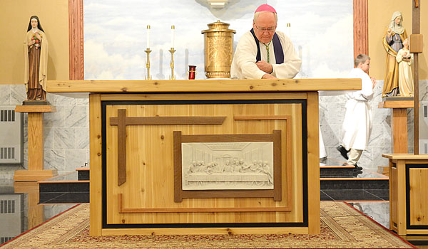 Bishop Richard J. Malone spreads oil with his hand to bless and dedicate the new altar at Sacred Heart of Jesus Church Bowmansville,
(Patrick McPartland/Staff Photographer)