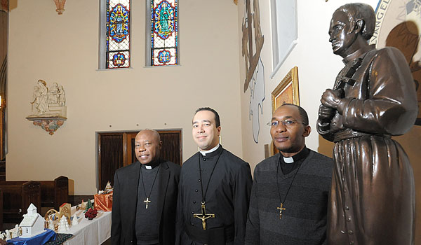 Father Quilin Bouzi, OMI (from left), Father David Muñoz, OMI, and Father Humphrey Milimo, OMI, stand beside a statue of the Oblates founder, St. Eugene de Mazenod, at Holy Angels Church in Buffalo. The Oblates of Mary Immaculate will celebrate their 200th anniversary this year. (Patrick McPartland/Staff Photographer)