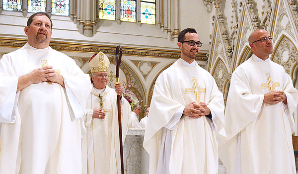 With Bishop Richard J. Malone behind them, three new priests for the Diocese of Buffalo stand before the congregation at the conclusion of the Rite of Ordination at St. Joseph Cathedral. There newly ordained priests are Father Michael Brown (left to right), Father Samuel Giangreco and Father Michael LaMarca.
(Patrick McPartland/Staff Photographer)
