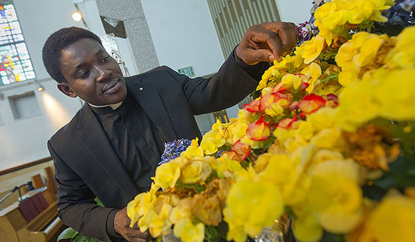Deacon Peter Bassey arranges the main floral centerpiece on the altar at the St. John Vianney Chapel at Christ the King Seminary. (Dan Cappellazzo/Staff Photographer)