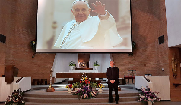 Msgr. Robert E. Zapfel, pastor of St. Leo the Great Parish in Amherst, stands before the large video screen which will project Pope Francis celebrating Mass live from Philadelphia on Sunday, Sept. 27, at 4 p.m. (Courtesy of St. Leo the Great Parish)