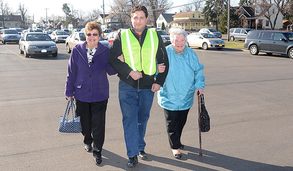 Parishioner Jim Cweirley (center) helps Carm Yuknke (left) and Doris Neff to and from their cars before Sunday Mass as part of the parking lot ministry at St. Amelia Church. (Patrick McPartland/Staff Photographer)