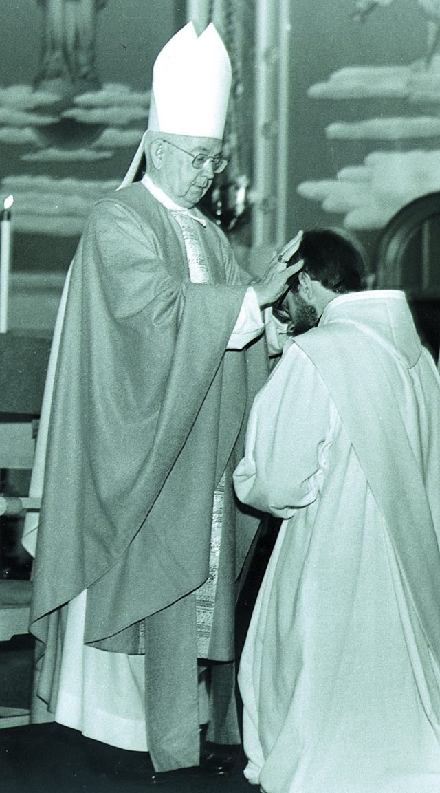 Bishop Bernard McLaughlin lays his hands on the head of Father McAdam during McAdam's ordination to the priesthood at Corpus Christi Church on July 12, 1980. No record exists of Fr. McAdam in Chancery. Information was gathered from the July issue of the C