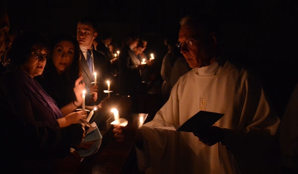 Rector Father Peter J. Drilling shares the light of his candle during the Easter Vigil Mass at St. Joseph Cathedral. (Patrick McPartland)