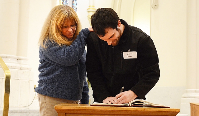 James Bauer signs the Book of the Elect as his sponsor, Bonnie Schiffmaker, looks on at the annual Rite of Christian Initiation for Adults Mass. This year the Mass was held at St. Joseph Cathedral.
(Patrick McPartland/Staff Photographer)