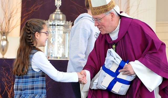 Bishop Richard J. Malone thanks Celia Crawford, a third-grader at St. John the Baptist School, for the gift of a sweat shirt. Bishop Malone was celebrating a special Mass at the parish in conjunction with the 