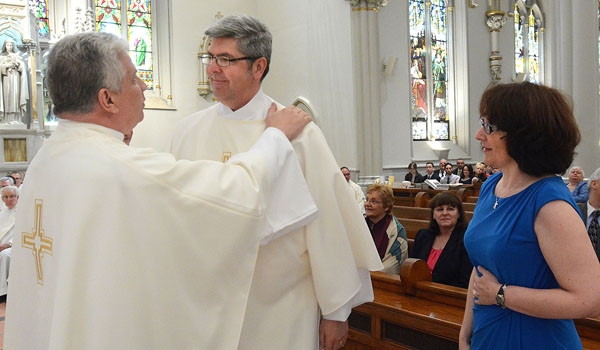 Peter Donnelly is vested by Father Joseph Gatto during ordination to the diaconate at St. Joseph Cathedral. Donnelly's wife Catherine watches.
(Patrick McPartland/Staff Photographer)