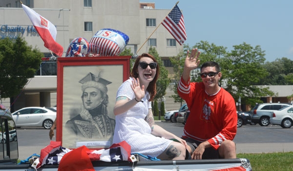 Revelers wave beside a portrait of General Pulaski as they make their way down Harlem Road as part of the Pulaski Day Parade in Cheektowaga.