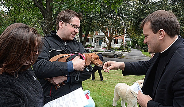 Snickers Walczak locks the hand of Father Ryszard Biernat as Veronika and Alan Walczak watch. All were on hand for the blessing of animals on the front lawn of the bishop's residence the day before the Feast of St. Francis. The tradition of blessing animals is conducted as a remembrance of St. Francis of Assisi's love for creation.