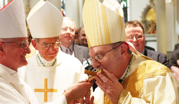 Out of reverence Bishop Edward Kmiec kisses a crucifix held by Auxiliary Bishop Edward Grosz as Bishop Kmiec is formally welcomed on behalf of the people of the Diocese of Buffalo.