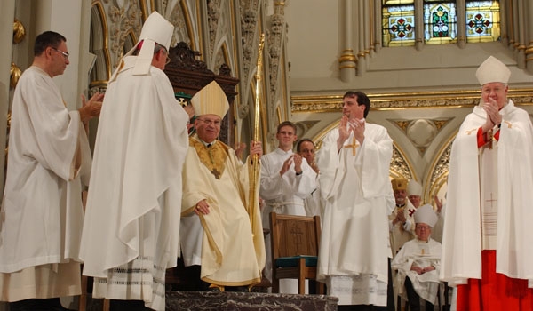 Bishop Edward Kmiec takes his place on the cathedra to a rousing applause during his installation as the 13th Bishop of the Diocese of Buffalo. The act of sitting in the cathedra symbolizes the authority that is vested in the bishop.