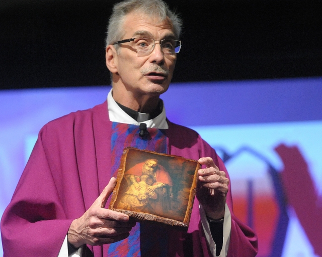 Father Eugene Ulrich, pastor of the Church of the Annunciation in Elma, gives his homily about the Prodigal Son using a depiction of Rembrant's showing the same theme at the 64th Annual Diocesan Youth Convention.