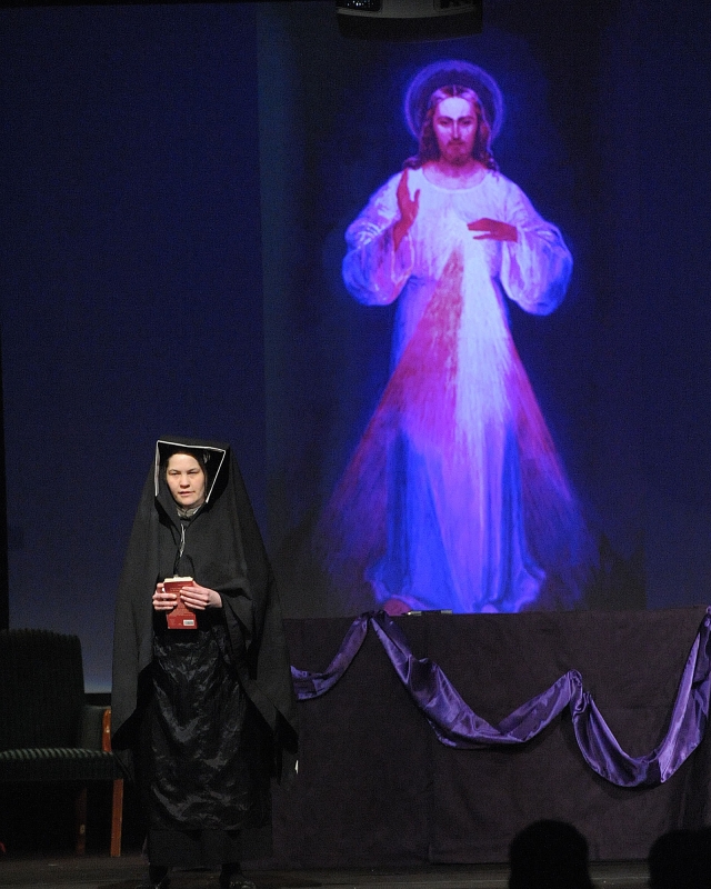 With the Divine Mercy depiction behind her,  Samantha Michel portrays St. Faustina before the Prayer for Mercy at the 64th Annual Diocesan Youth Convention. Selections of St. Faustina's diary were read throughout the convention.