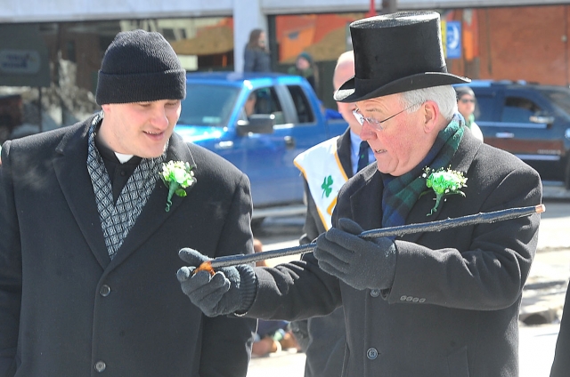 Bishop Richard J. Malone shows his Blackthorn cane to his secretary, Father Ryszard Biernat, as the pair marches in the 2014 St. Patrick's Day Parade along Delaware Avenue in the City of Buffalo.