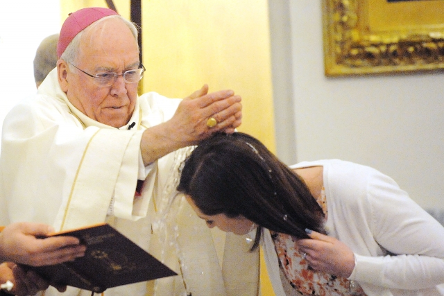 Bishop Richard J. Malone baptizes Stephanie Galuszka as part of the Easter Vigil at St. Joseph Cathedral, Buffalo, on Saturday night.