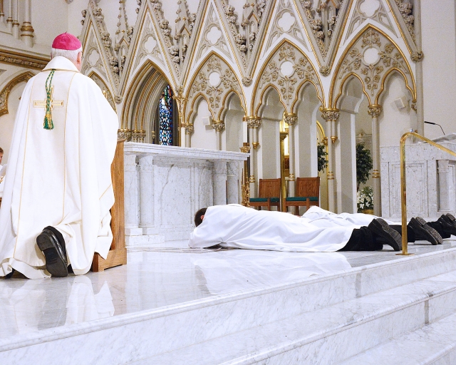 As a sign of total commitment, the three candidates for ordination lie prostrate at St. Joseph Cathedral on May 28, 2016.
