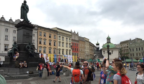 Sarah Leahy, from the diocesan Department of Youth and Young Adult Ministry, leads a group of young adults through Krakow's City Square on the morning of Thursday, July 29. (Patrick J. Buechi/Staff)