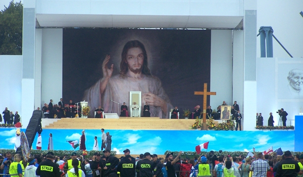 Pope Francis and Polish dignitaries sit in front of an copy of the Divine Mercy icon. The pope made his first public appearance of World Youth Day at a welcoming ceremony, to deliver a message of encouragement to teen and young adult Catholics from around