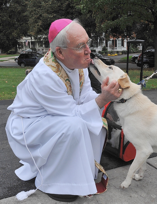 Bishop Richard Malone gets a lick from Gunnar a golden retriever as the bishop holds a pet blessing for the feast of St. Francis of Assisi on the front lawn of the bishop's residence in Buffalo.