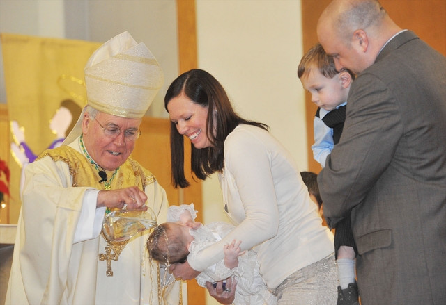 During Mass at St. Anthony Worship Site, Batavia, Bishop Malone baptizes Sadie Lynn Fix with her parents Daniel Fix and Gretchen Gautieri, her bother Luka Fix and godparents Aaron and Kristen Fix.