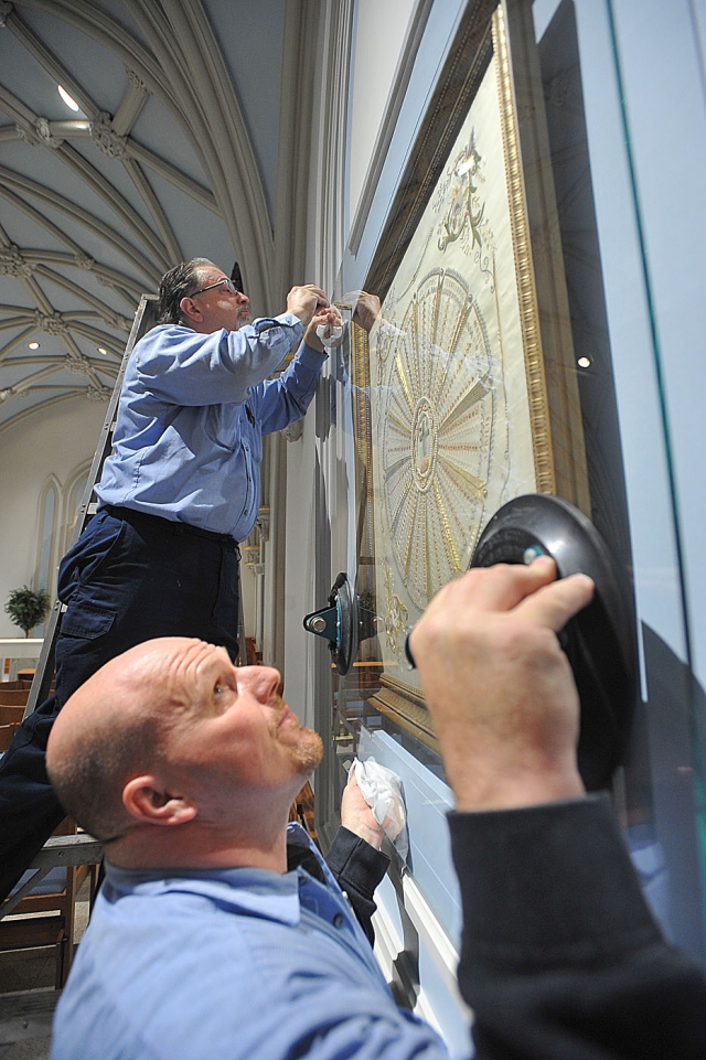 Robert Battleson (above) and Steven Gorcheck of Frontier Glass carefully install safety glass over a cloth reliquary, containing first-class relics of 366 saints. The reliquary was installed inside the Mary Chapel at St. Joseph Cathedral after having been lost for about 100 years. 