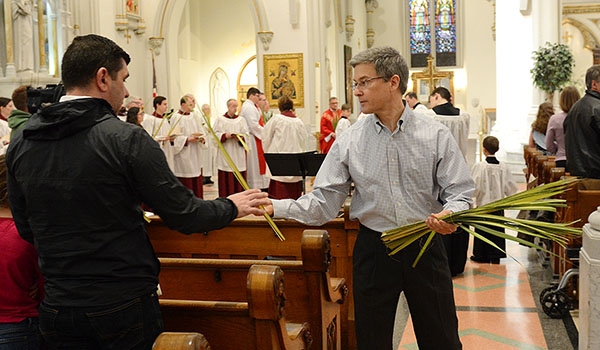 Usher Kevin Spencer gives palms to those attending Palm Sunday Mass at St. Joseph Cathedral. (Patrick McPartland/Managing Editor)