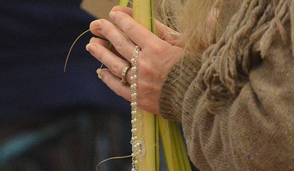 Palms and a rosary are held by a woman as she prays during Palm Sunday Mass at St. Joseph Cathedral. (Patrick McPartland/Managing Editor)